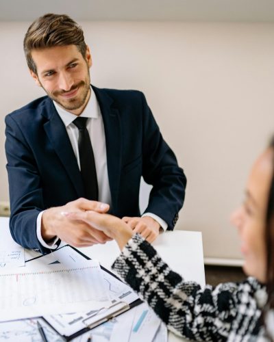 A Smiling Man Shaking Hands with a Person at an Office